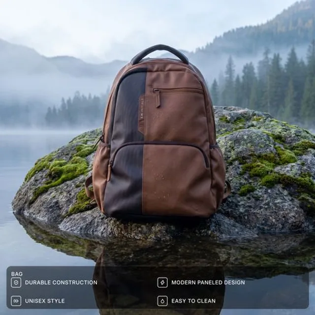 A brown backpack resting on a moss-covered rock beside a misty mountain lake